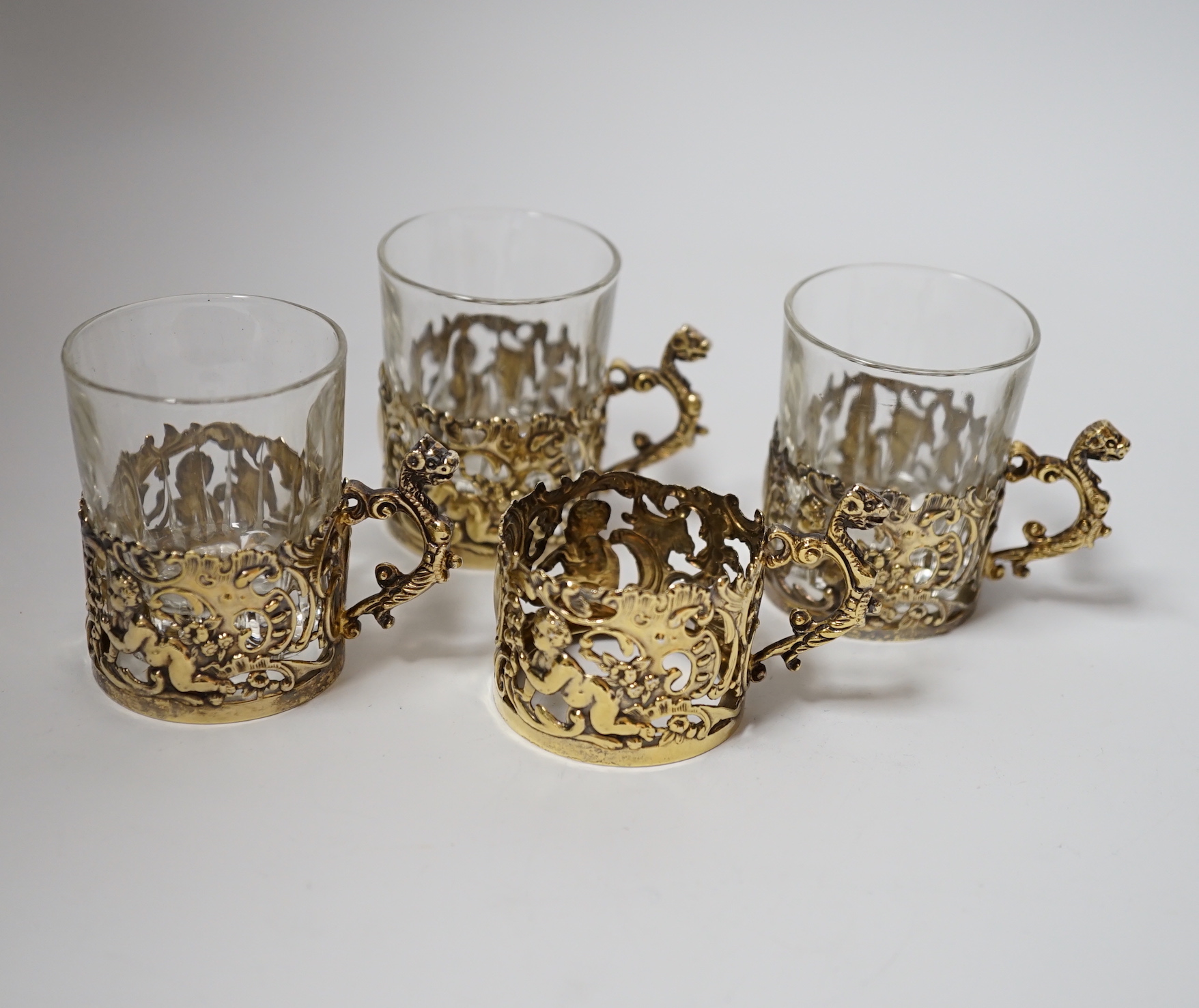 A set of four late Victorian pierced silver gilt coffee can holders, by William Comyns, Birmingham, 1897, with three glass inserts only